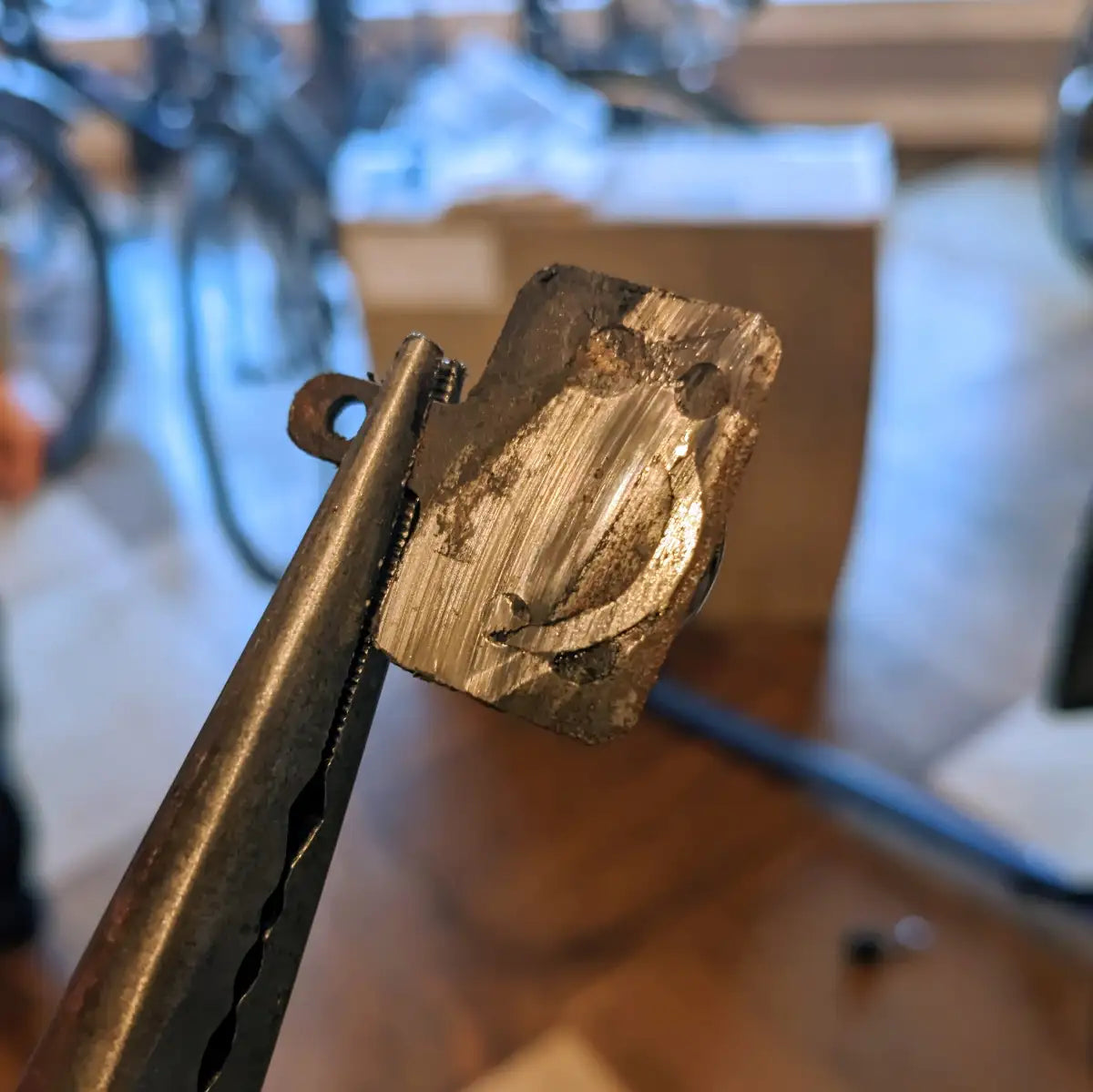 Picture showing hydraulic brake pads worn completely through to the piston. The piston has been ground away. 